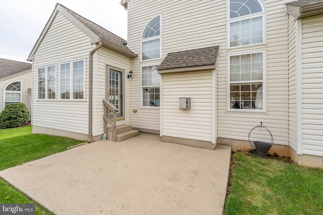 back of house featuring entry steps, a patio area, and a shingled roof
