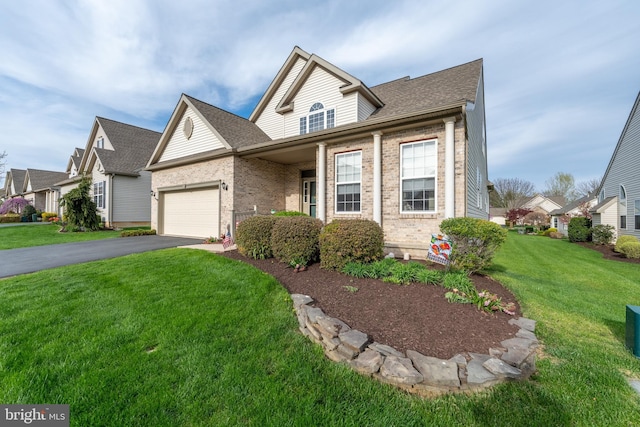 traditional-style house with asphalt driveway, brick siding, a front lawn, and an attached garage