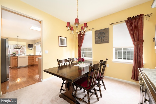 dining room featuring a chandelier, light colored carpet, and baseboards