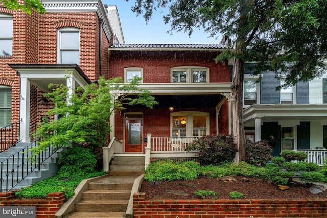 view of front of home with a porch, brick siding, a tiled roof, and stairs