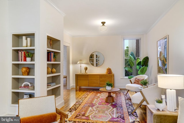 living area featuring ornamental molding, wood finished floors, baseboards, and built in features