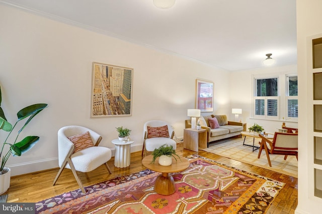 sitting room featuring wood-type flooring, baseboards, and ornamental molding