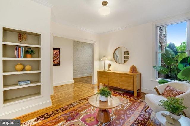 sitting room featuring baseboards, crown molding, and light wood-style floors