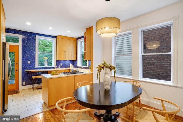 kitchen with stainless steel appliances, light wood finished floors, baseboards, a peninsula, and recessed lighting