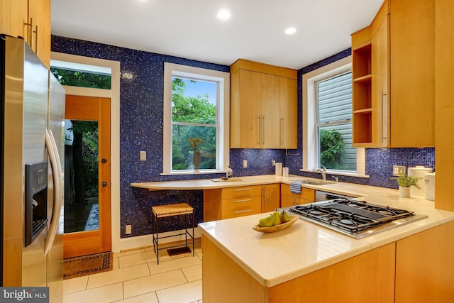 kitchen with stainless steel appliances, light countertops, decorative backsplash, a sink, and recessed lighting