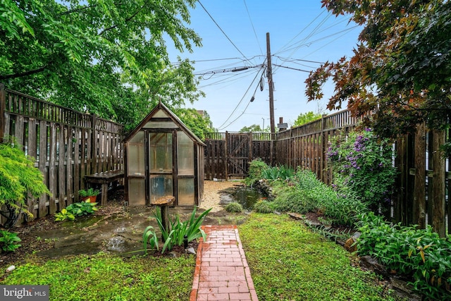 fenced backyard featuring a greenhouse and an outdoor structure