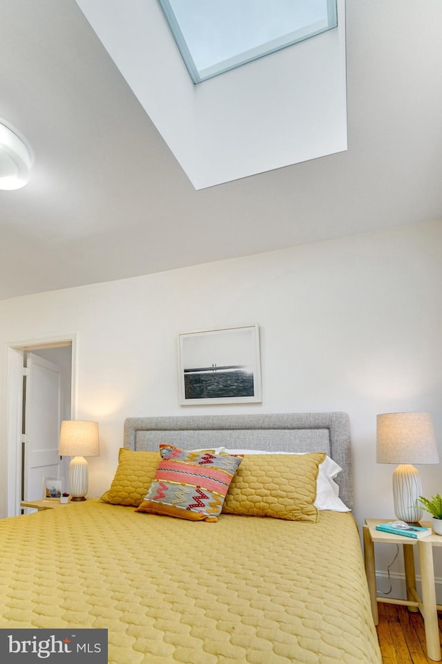 bedroom featuring a skylight and wood finished floors