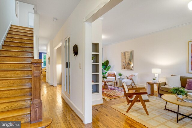foyer entrance featuring light wood-type flooring, stairway, and baseboards