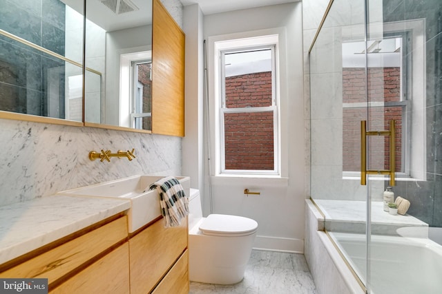 bathroom featuring toilet, marble finish flooring, vanity, baseboards, and decorative backsplash