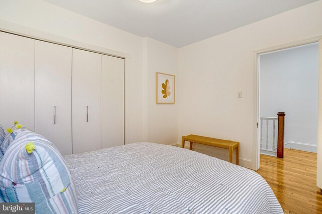 bedroom with light wood finished floors, a closet, and baseboards