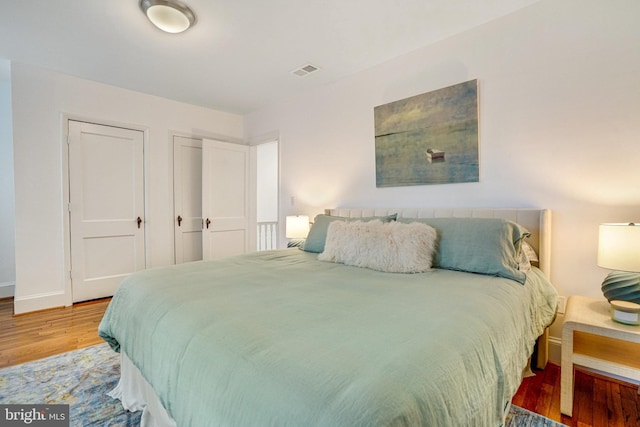 bedroom featuring wood finished floors, baseboards, and multiple closets