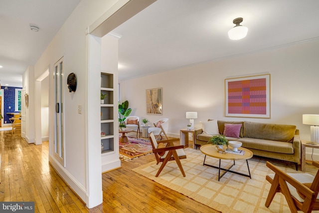 living room featuring hardwood / wood-style flooring, built in features, and baseboards