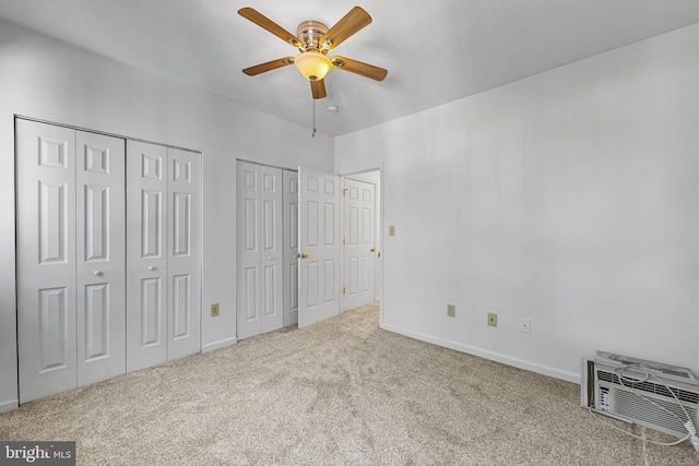 unfurnished bedroom with two closets, carpet floors, baseboards, and ceiling fan