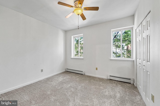 carpeted spare room featuring a baseboard radiator, baseboards, and a ceiling fan