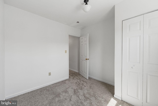 unfurnished bedroom featuring carpet, baseboards, and a closet