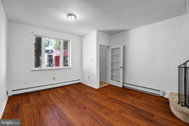 unfurnished bedroom with a baseboard heating unit, wood finished floors, and baseboards