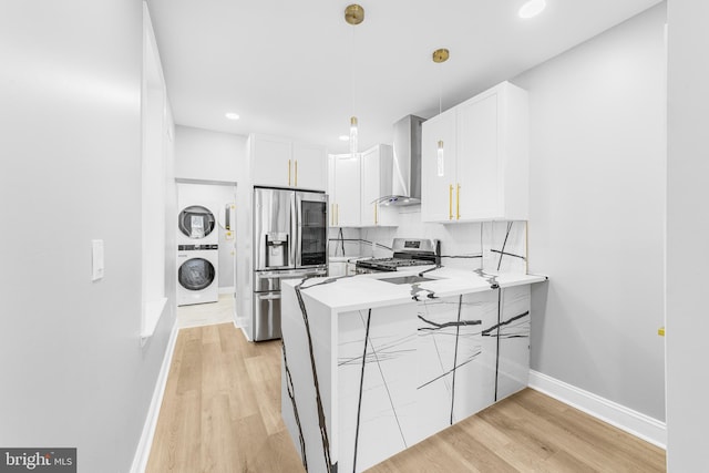 1615 Fillmore St, Philadelphia, PA 19124 - kitchen featuring wall chimney range hood, stainless steel appliances, stacked washer / drying machine, a peninsula, and white cabinets