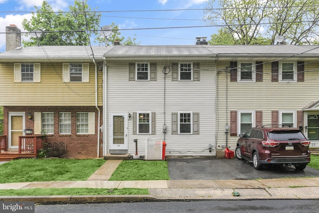 townhome / multi-family property featuring a chimney, brick siding, and a front yard