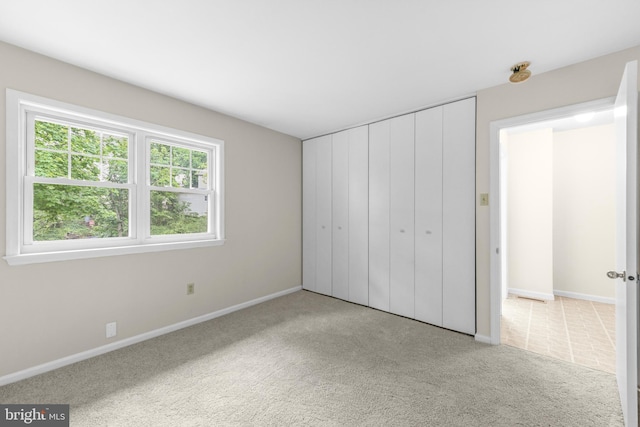unfurnished bedroom with carpet flooring, baseboards, and a closet