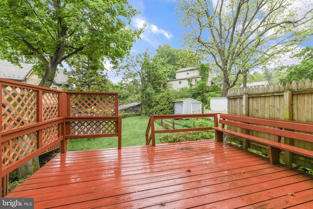 deck featuring a storage unit, a fenced backyard, and an outbuilding