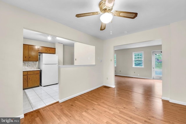 unfurnished living room with a ceiling fan, light wood-type flooring, and baseboards