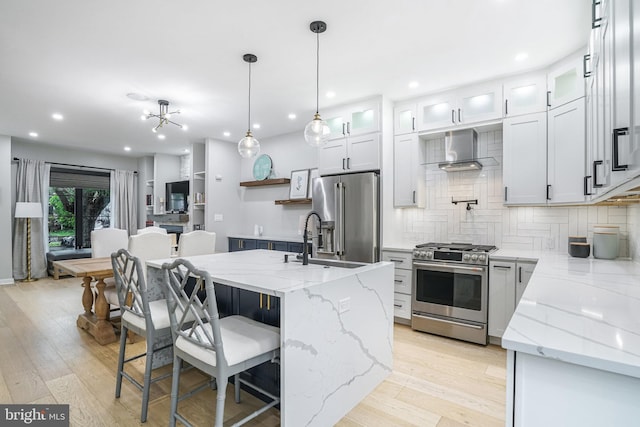 603 N Alfred St, Alexandria, VA 22314 - kitchen featuring appliances with stainless steel finishes, wall chimney range hood, a sink, backsplash, and light wood-style floors