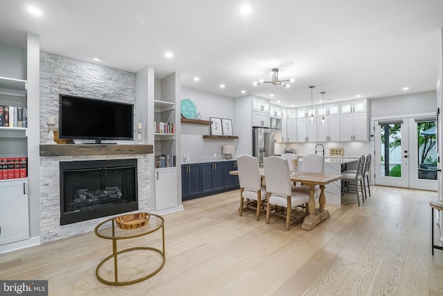 603 N Alfred St, Alexandria, VA 22314 - dining room with a chandelier, light wood-style floors, a stone fireplace, recessed lighting, and french doors