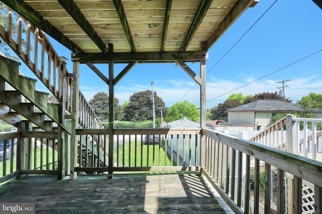 wooden terrace featuring stairs and a yard