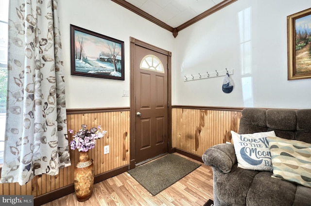 foyer entrance featuring crown molding, a wainscoted wall, wood finished floors, and wooden walls