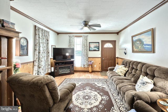 living room featuring wainscoting, a ceiling fan, crown molding, wood finished floors, and wooden walls