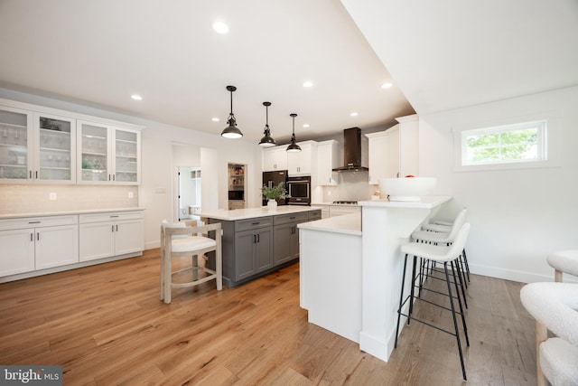 1051 Glen Hall Rd, Kennett Square, PA 19348 - kitchen with wall oven, a breakfast bar area, wall chimney range hood, gray cabinets, and decorative backsplash