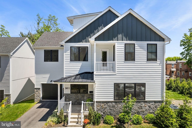 view of front facade featuring stone siding, board and batten siding, driveway, a porch, and a standing seam roof