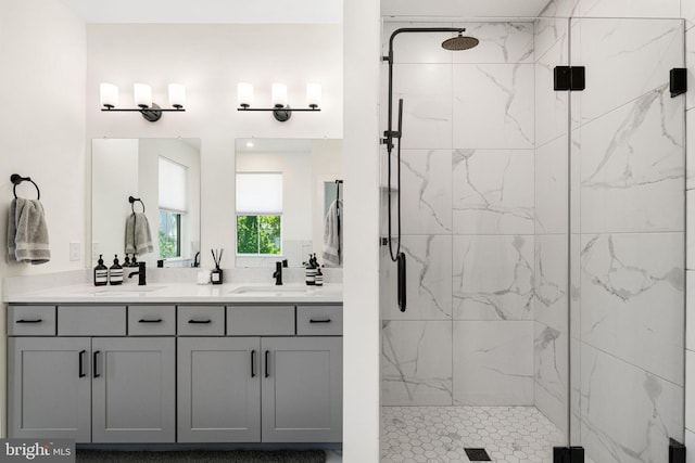 full bath with a marble finish shower and double vanity