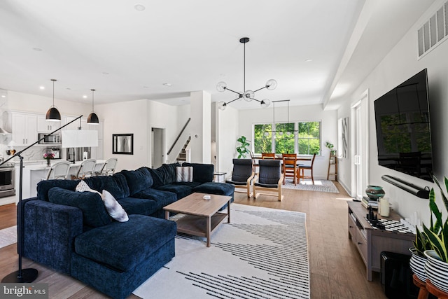 living area with stairs, wood finished floors, and a chandelier