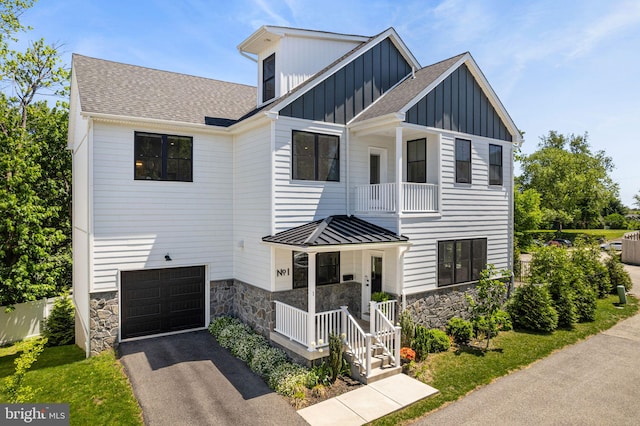 modern farmhouse with board and batten siding, a porch, stone siding, an attached garage, and a shingled roof