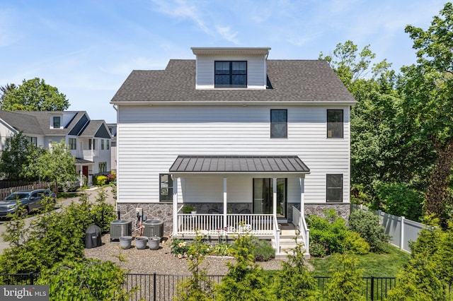back of property with stone siding, cooling unit, and covered porch
