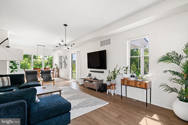 living area with healthy amount of natural light, a chandelier, wood finished floors, and baseboards