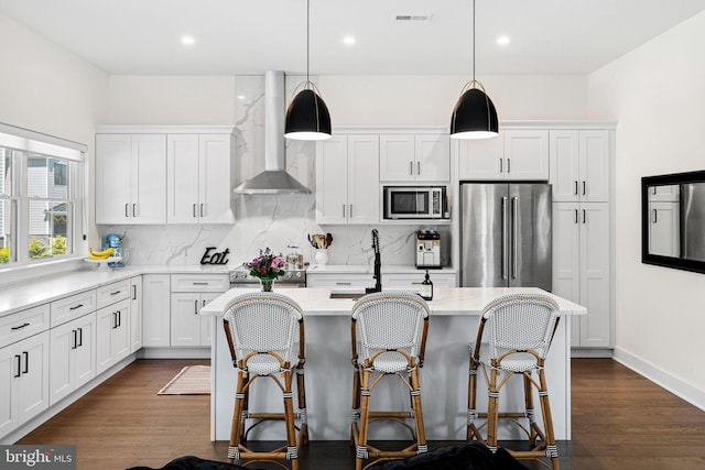 kitchen featuring wall chimney range hood, appliances with stainless steel finishes, decorative backsplash, white cabinets, and recessed lighting