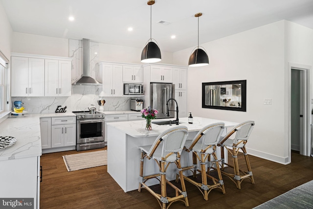 kitchen featuring wall chimney range hood, appliances with stainless steel finishes, a sink, dark wood-type flooring, and recessed lighting