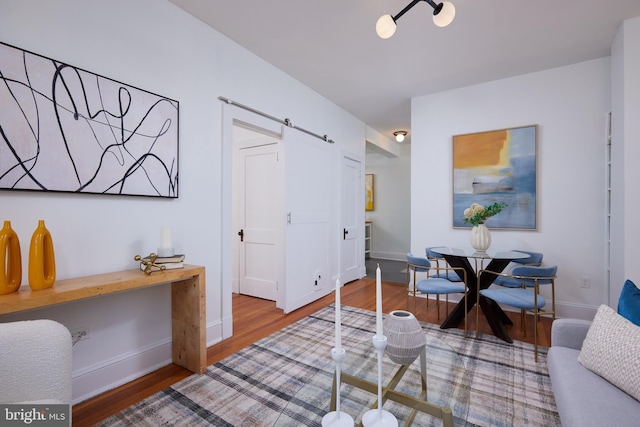 living area featuring a barn door, wood finished floors, and baseboards