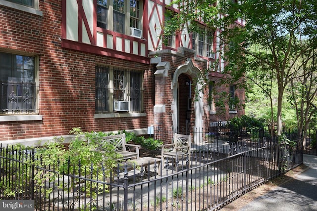 entrance to property featuring fence, brick siding, a patio area, and cooling unit
