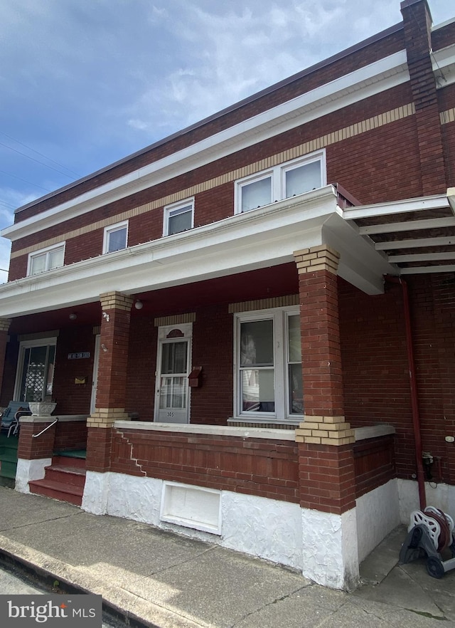 multi unit property with brick siding and a porch