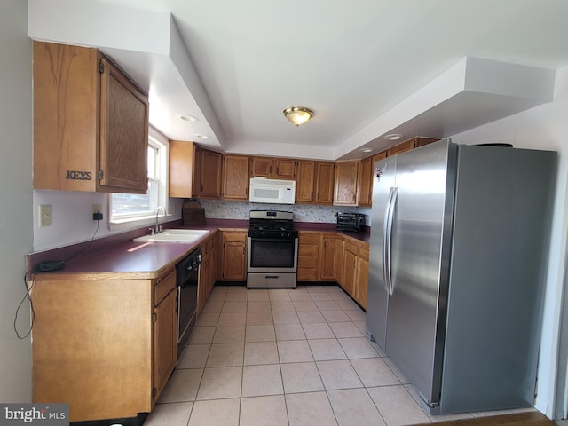 17 W Delaware Dr, Little Egg Harbor Twp, NJ 08087 - kitchen featuring appliances with stainless steel finishes, a sink, light tile patterned flooring, brown cabinetry, and a tray ceiling