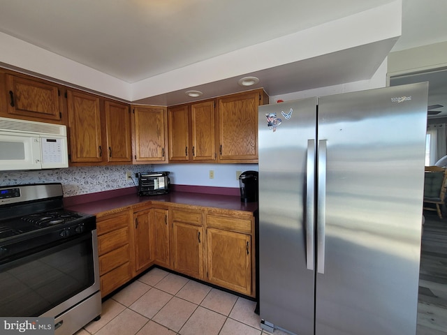 17 W Delaware Dr, Little Egg Harbor Twp, NJ 08087 - kitchen featuring appliances with stainless steel finishes, brown cabinets, light tile patterned flooring, and dark countertops