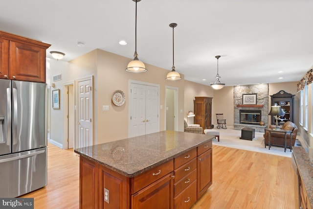 1490 Jakes Creek Dr, Woodbine, MD 21797 - kitchen featuring stainless steel refrigerator with ice dispenser, light wood-type flooring, a stone fireplace, hanging light fixtures, and a kitchen island
