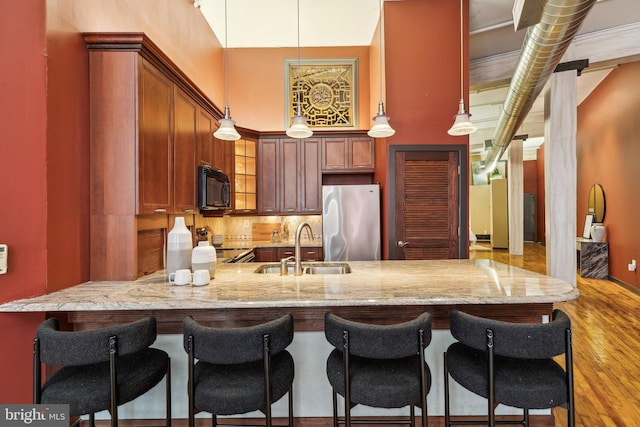 428 N 13th St Unit 3G, Philadelphia, PA 19123 - kitchen with appliances with stainless steel finishes, a sink, a peninsula, light stone counters, and a breakfast bar area