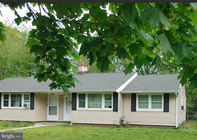ranch-style house with a chimney, a front lawn, and a shingled roof