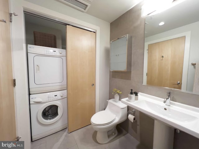 1133 14th St NW Unit 1005, Washington, DC 20005 - half bathroom featuring stacked washer / dryer, toilet, and tile patterned floors