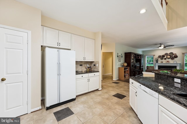 kitchen with white appliances, a fireplace, white cabinets, a ceiling fan, and tasteful backsplash