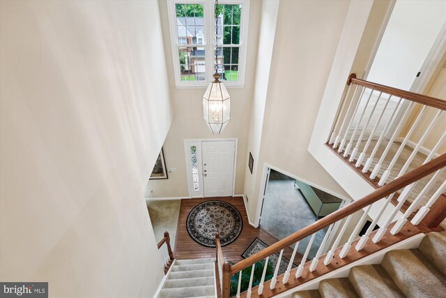 entryway featuring stairway, wood finished floors, a towering ceiling, and baseboards
